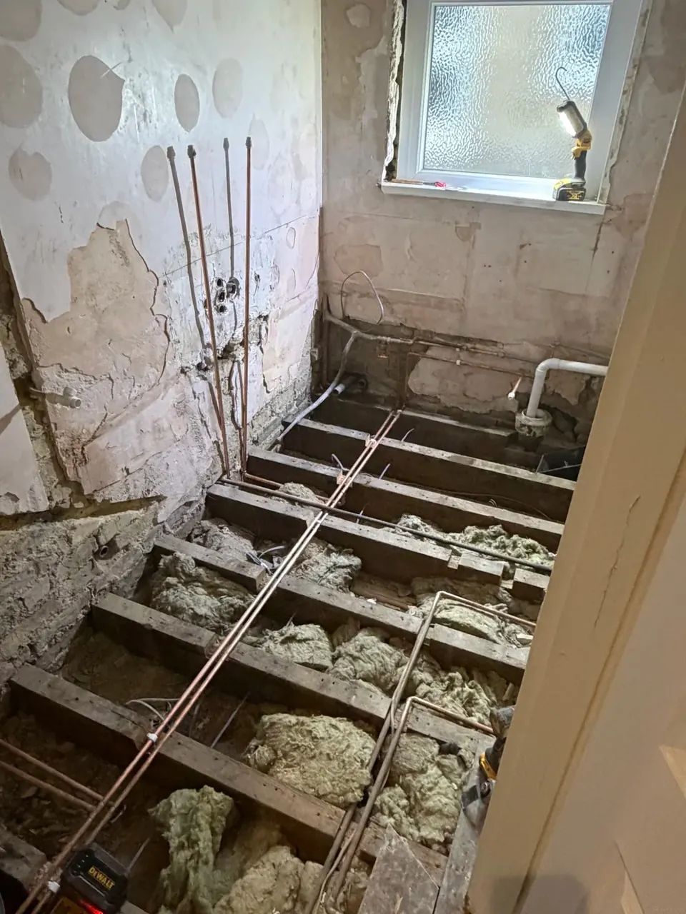 Bathroom floor opened during refurbishment showing new pipework
