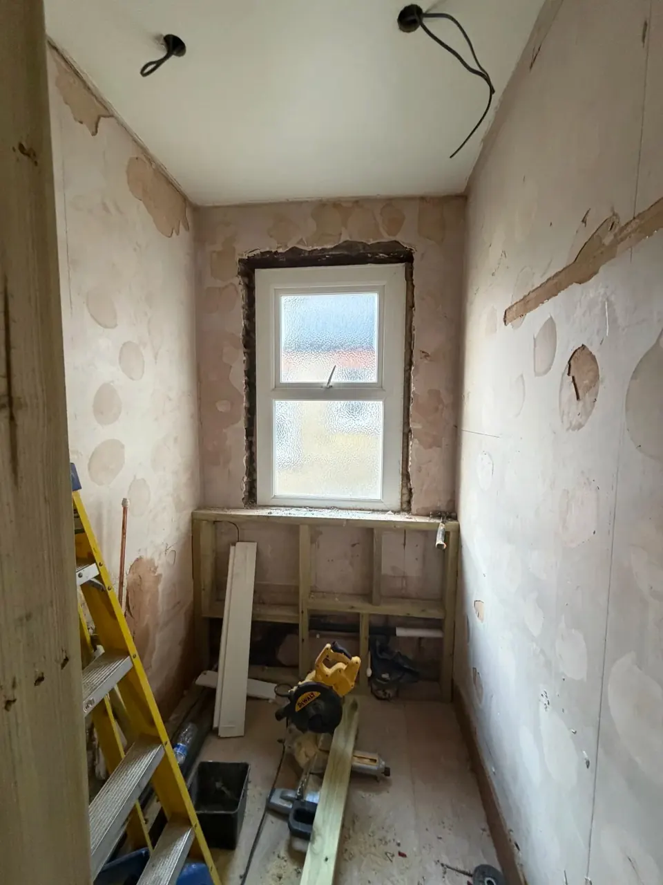 Bathroom walls stripped back around the window during refurbishment