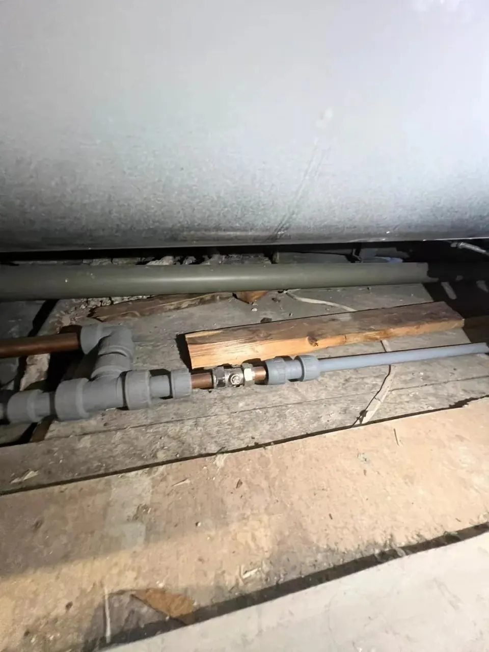 Close-up of plumbing connection beneath bathroom floor